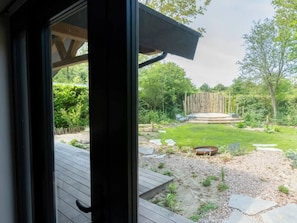 Blick auf einen Garten mit einer Holzterrasse, einer Rasenfläche und einem Holzzaun.