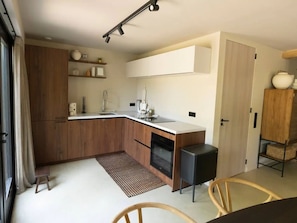 A compact kitchen with wooden cabinets, a built-in oven, and a small refrigerator. - Vacation home near the North Sea beach. (Kamperland)