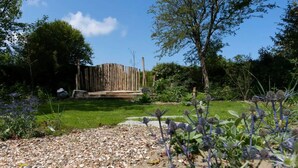 A garden with a wooden fence, a gravel path, and various plants. - Vacation home near the North Sea beach. (Kamperland)