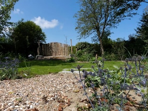 Ein Garten mit Holzzaun, Kiesweg und verschiedenen Pflanzen.
