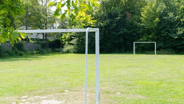 A grassy field with a white goalpost and another goalpost in the distance. - Vacation home near the North Sea beach. (Kamperland)