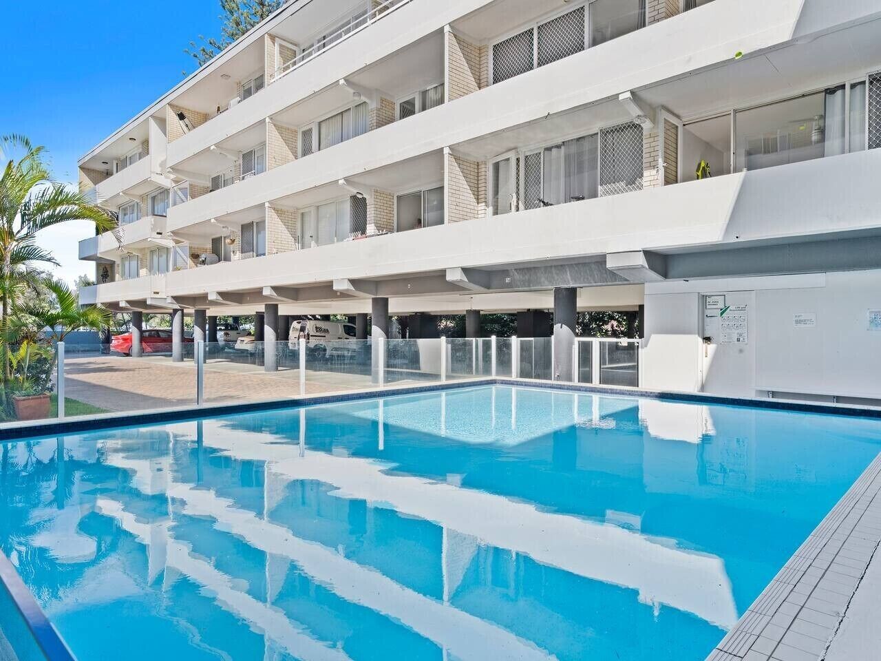 Un hôtel moderne doté d’une piscine, de nombreux balcons et d’un espace de stationnement.