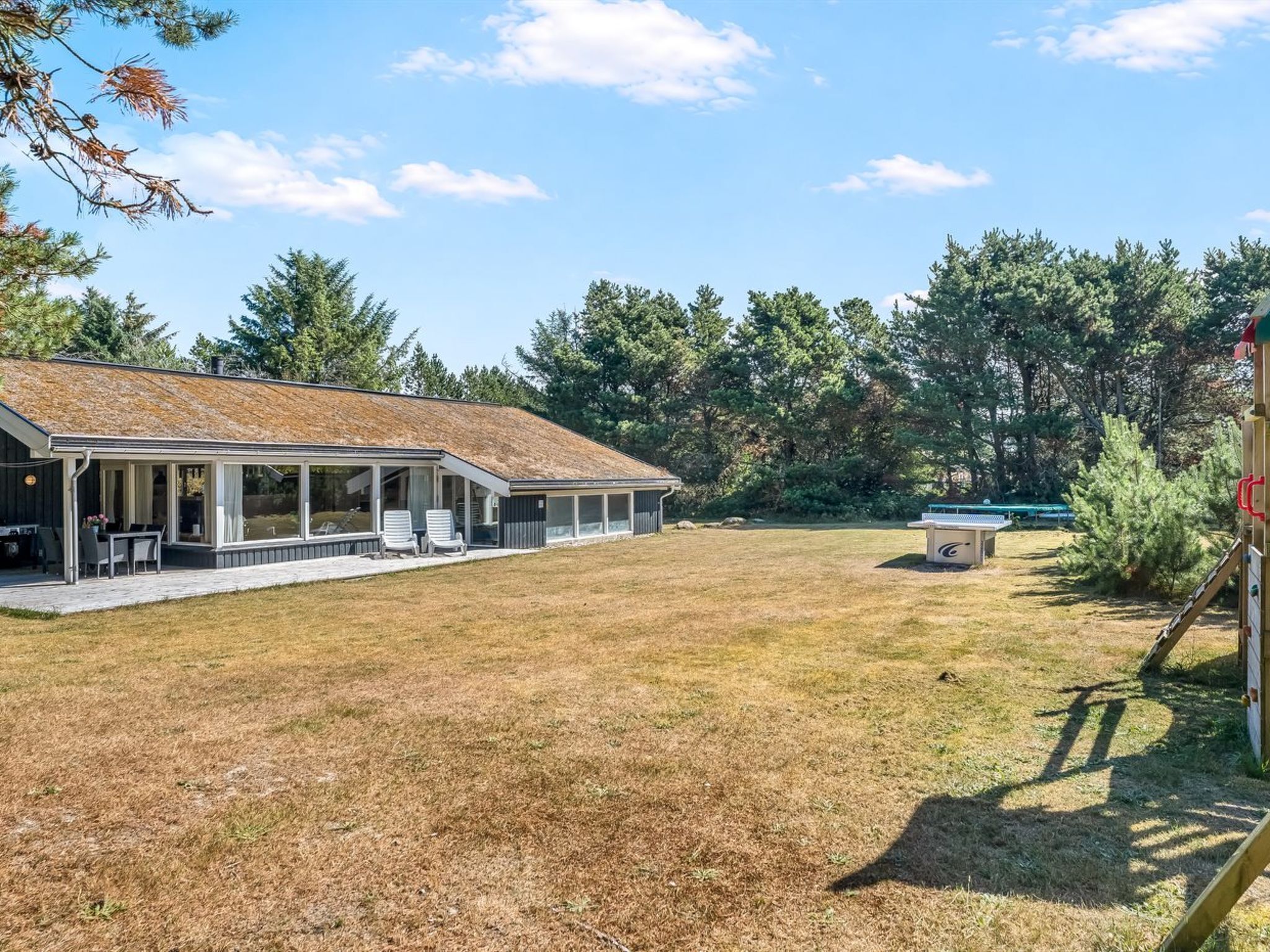 A single-story building with a covered patio area, a grassy yard, and a playground.