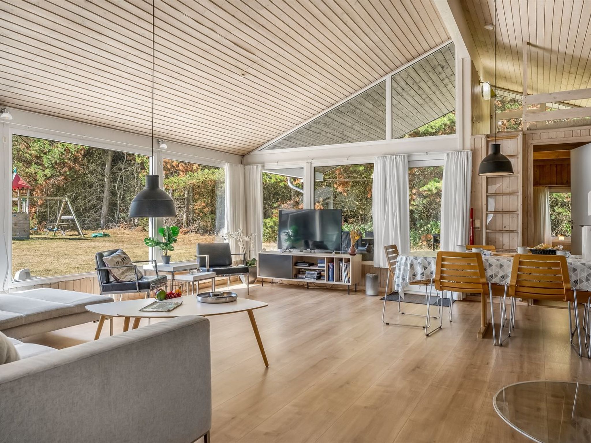 A spacious living room with a large TV, comfortable seating, and a view of the outdoors.