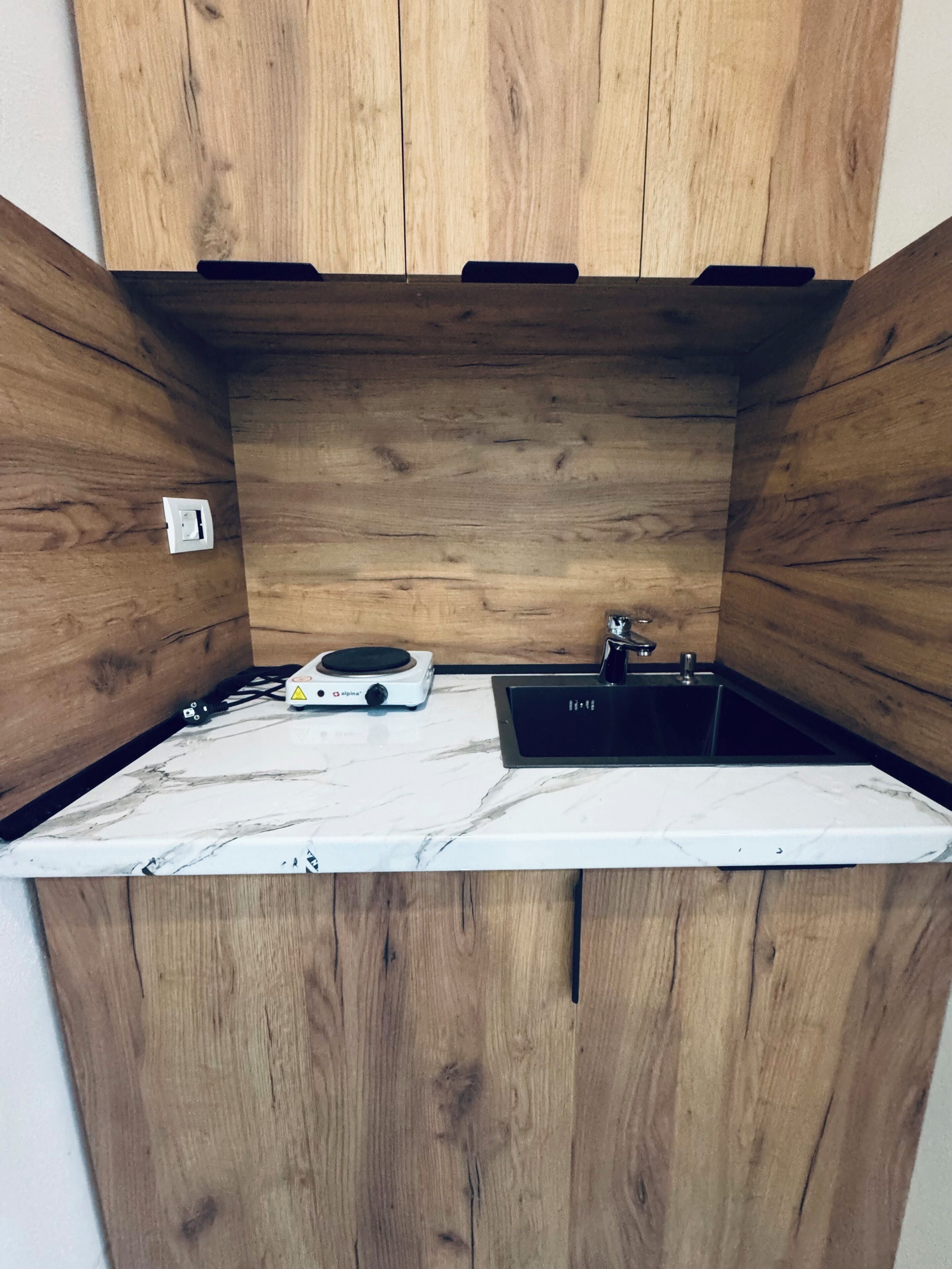 Una cocina compacta con muebles de madera, un lavamanos integrado y una encimera con estufa.