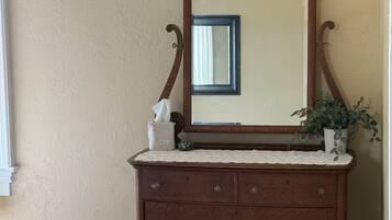 A wooden dresser with a mirror, a tissue box, and a plant.