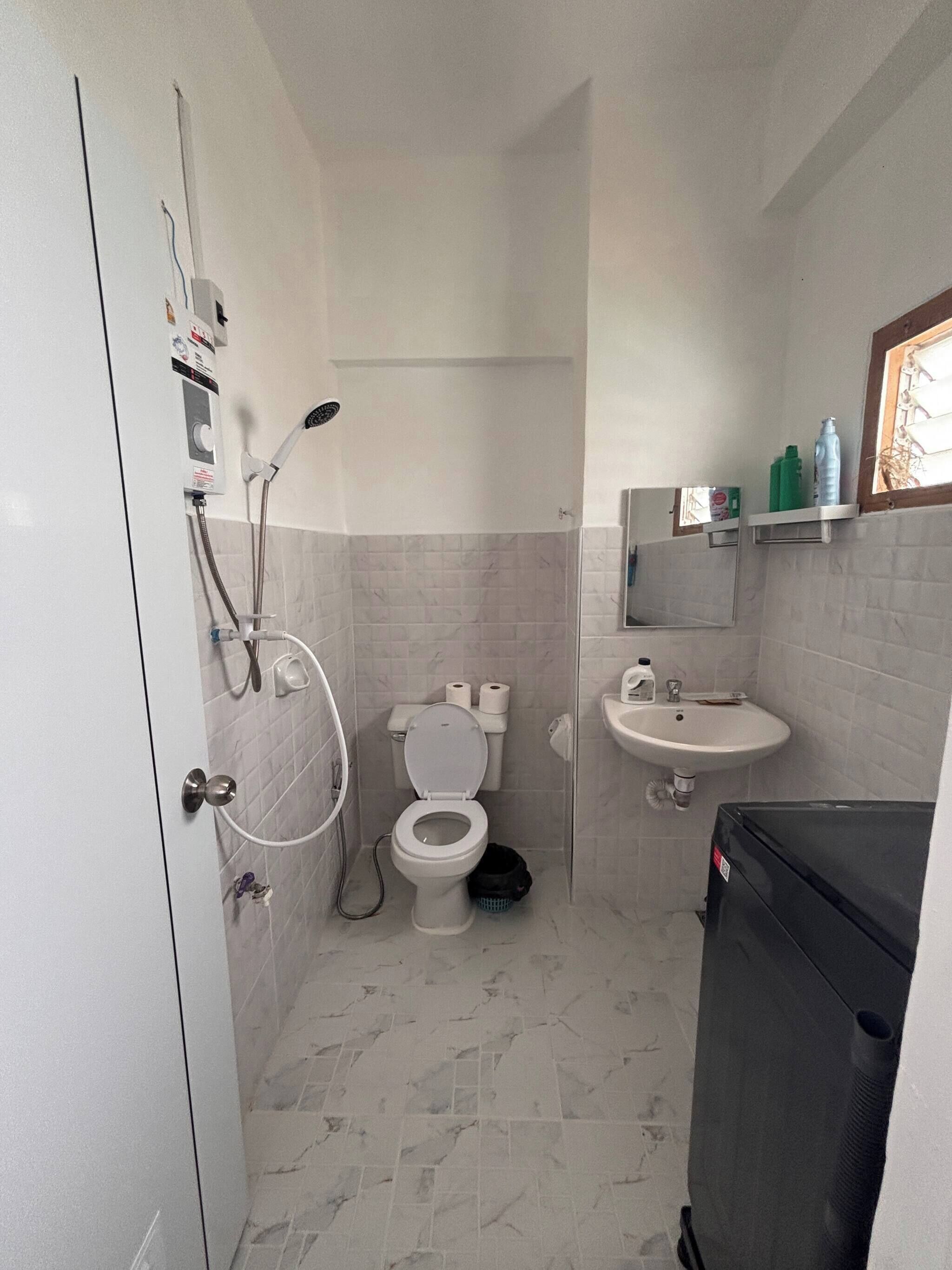 Un baño pequeño con inodoro, lavamanos y ducha.