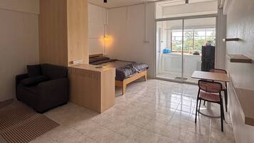 Interior moderno com uma cama, uma mesa, uma cadeira e vista através de uma porta de vidro.