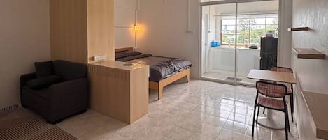 Un interior moderno con una cama, un escritorio, una silla y vistas a través de un ventanal.