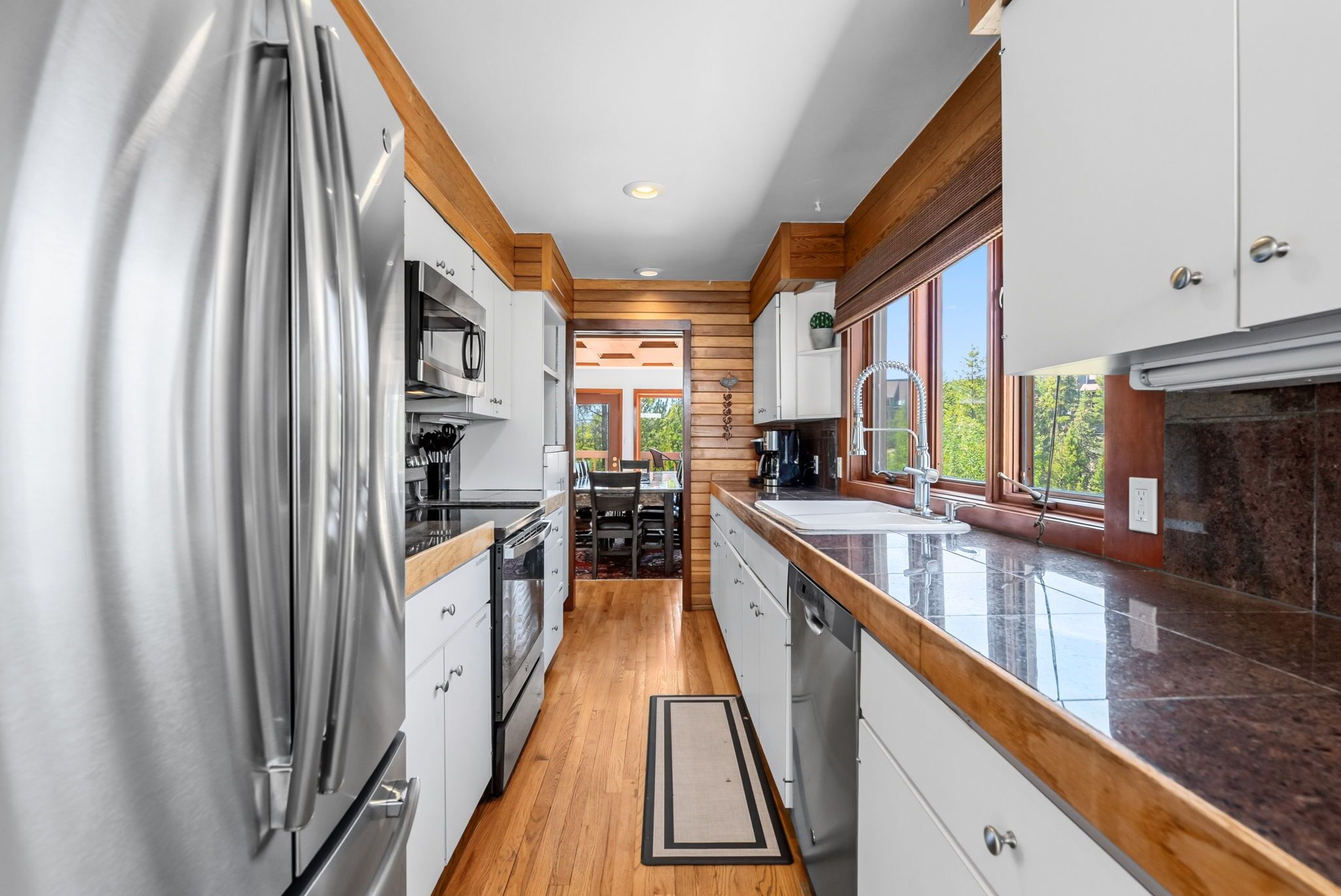 A modern kitchen with stainless steel appliances, wooden accents, and a view to the outdoors.