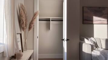 A room with a white door, a sofa, a small table with a vase, and pampas grass.