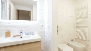Ein modernes Badezimmer mit einem großen Spiegel, einem Waschbecken, einer Badewanne und einer Toilette.