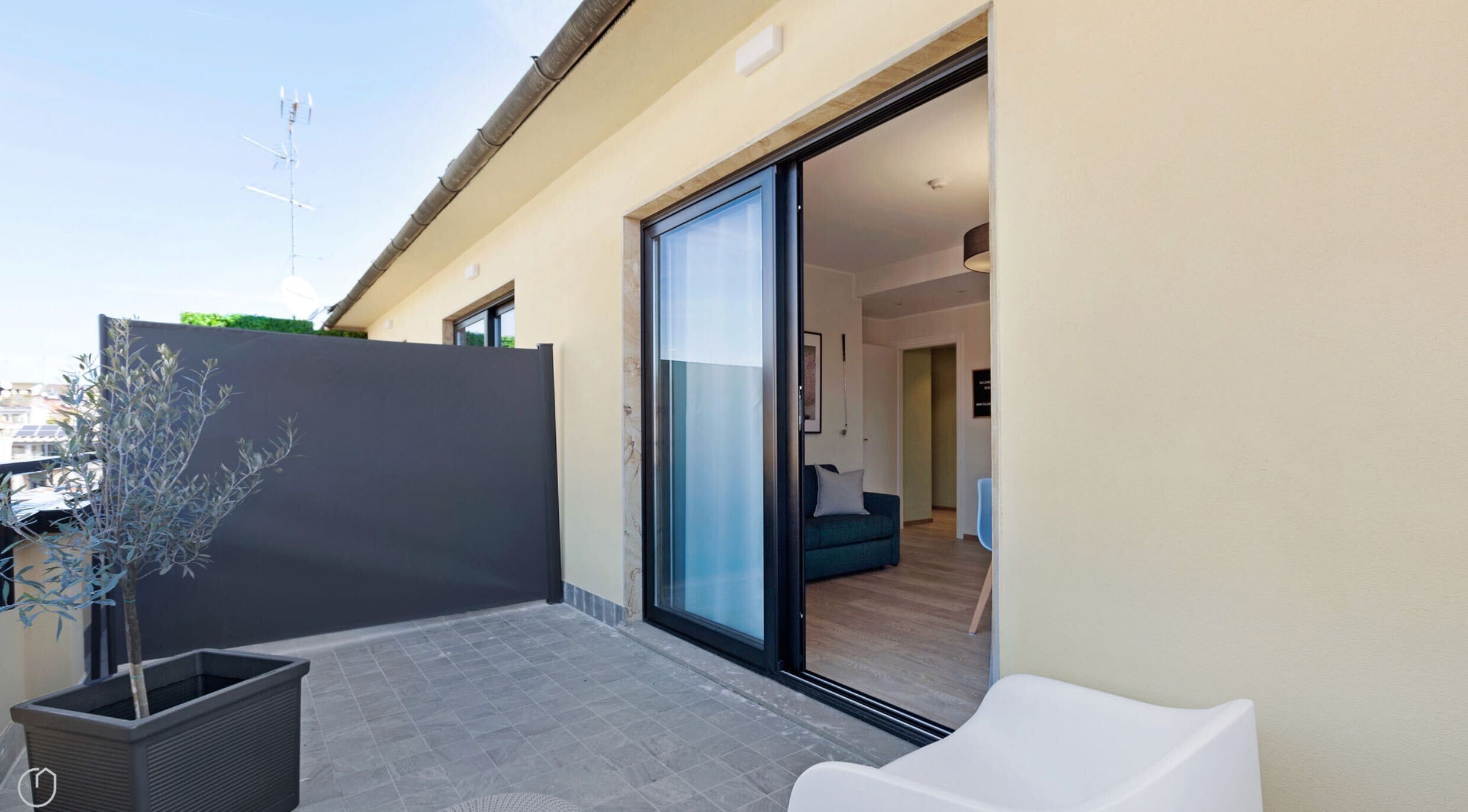 Un patio moderno al aire libre con un ventanal corredizo que da a una sala de estar.