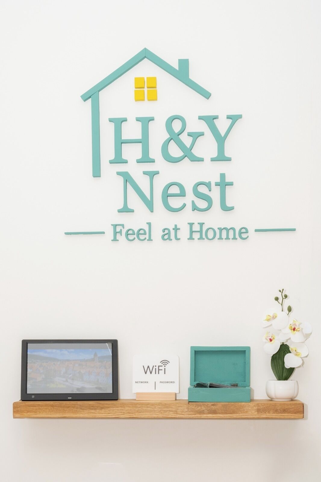 Une enseigne murale avec l’inscription « H&Y Nest, comme chez soi » et, en dessous, un symbole indiquant la présence d’une connexion Wi-Fi.