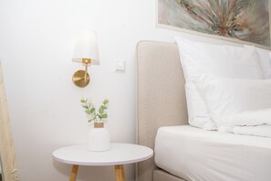 A neatly arranged hotel room with a bed, a round white table with a lamp, and a small plant.