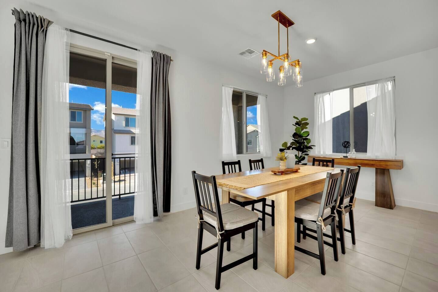 A dining area with a wooden table, six chairs, and a modern chandelier.