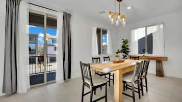 A dining area with a wooden table, six chairs, and a modern chandelier.