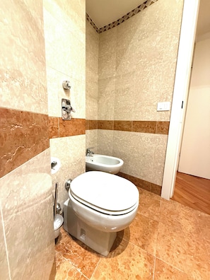 A bathroom with a toilet, bidet, and a shower area. - DOUBLE ROOM WITH PRIVATE BATHROOM (Milano)