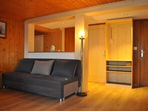 Ein Zimmer mit einer Couch, einer Stehlampe und einer Holztür.