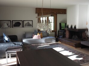 Uma sala de estar com sofá, mesa de centro, lareira e televisão.