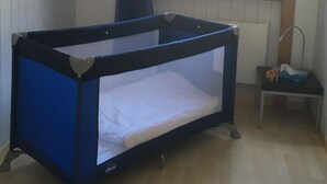Um quarto com uma cama beliche, janela com cortinas, radiador e uma pequena mesa com abajur.