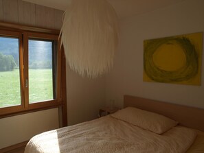 Quarto com cama, janela e um quadro na parede.