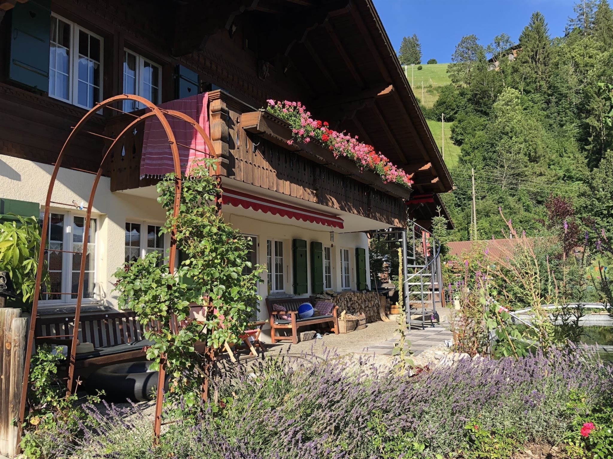 Un chalet tradizionale con facciata in legno, un balcone fiorito e un giardino con lavanda.