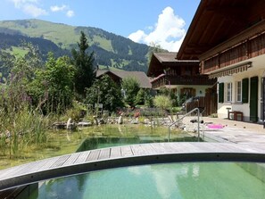 A wooden deck leading to a clear pool with a mountain backdrop. - Strubeli Appartement/Fewo, Dusche oder Bad, WC, 2 Schlafräume 4-Bett-Wohnung by Interhome (St Stephan)