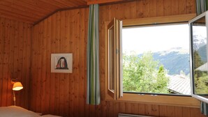 A wooden-paneled room with a bed, a window with curtains, and a framed picture on the wall. - Sumpfbödeli Appartement/Fewo, Badewanne, 3 Schlafräume 6-Bett-Wohnung by Interhome (Lenk)