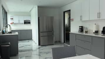 A modern kitchen with a stainless steel refrigerator, white cabinets, and a marble floor.