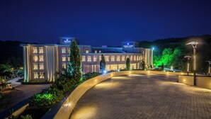 A hotel with a modern design, featuring a curved driveway and well-lit entrance.