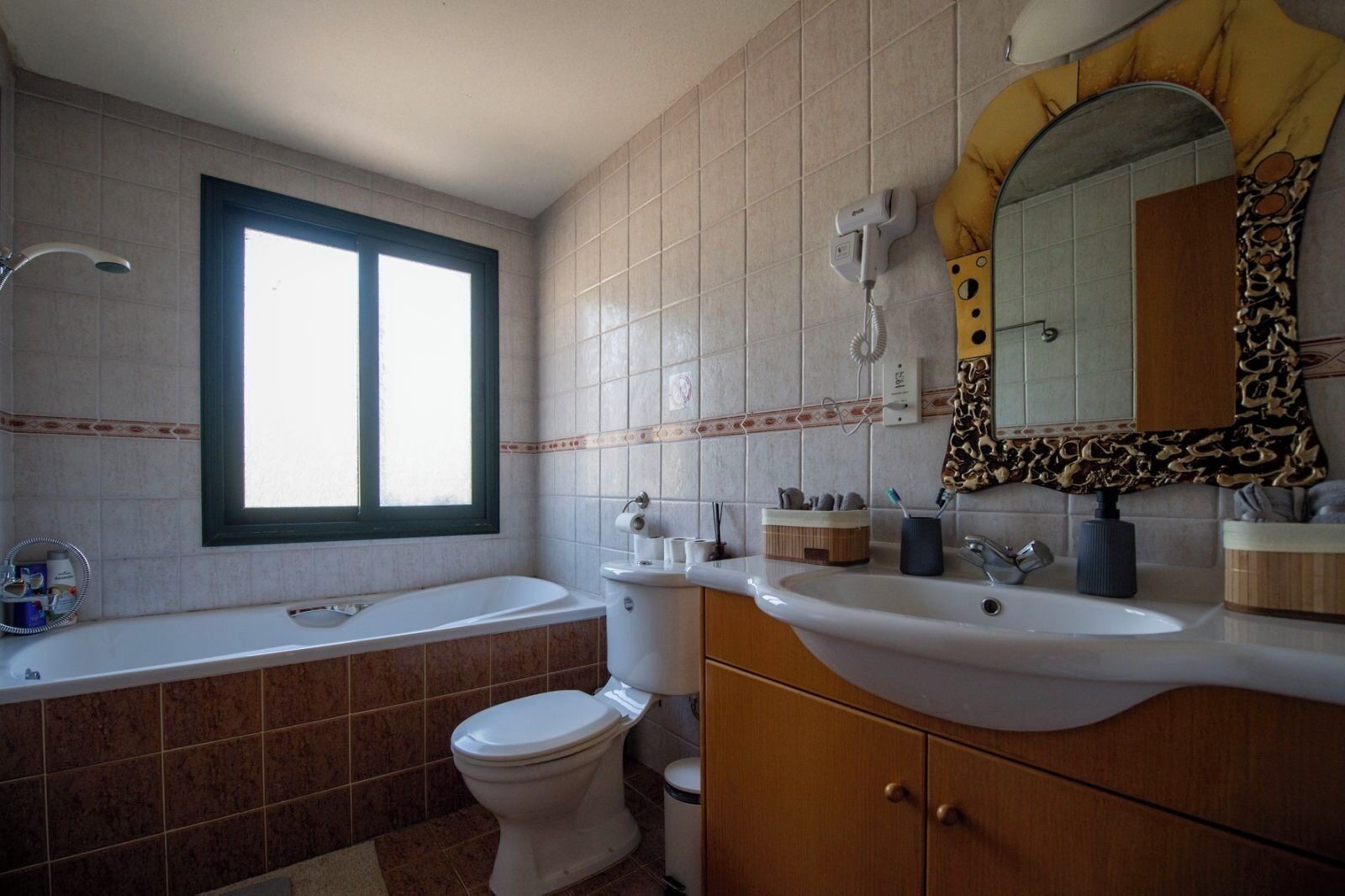 Ein Badezimmer mit Badewanne, Toilette, Waschbecken und einem Spiegel mit dekorativem Rahmen.