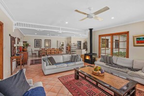 A spacious living area with a fireplace, sofas, a dining table, and a ceiling fan. - Wahroonga Luxury Estate in Kangaroo Valley (Kangaroo Valley)