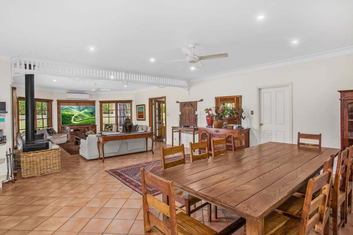 A spacious living area with a wooden dining table, a fireplace, and a large window with a view of greenery.