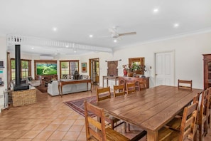 A spacious living area with a wooden dining table, a fireplace, and a large window with a view of greenery. - Wahroonga Luxury Estate in Kangaroo Valley (Kangaroo Valley)