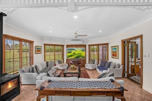 A spacious living room with a fireplace, comfortable seating, and large windows. - Wahroonga Luxury Estate in Kangaroo Valley (Kangaroo Valley)