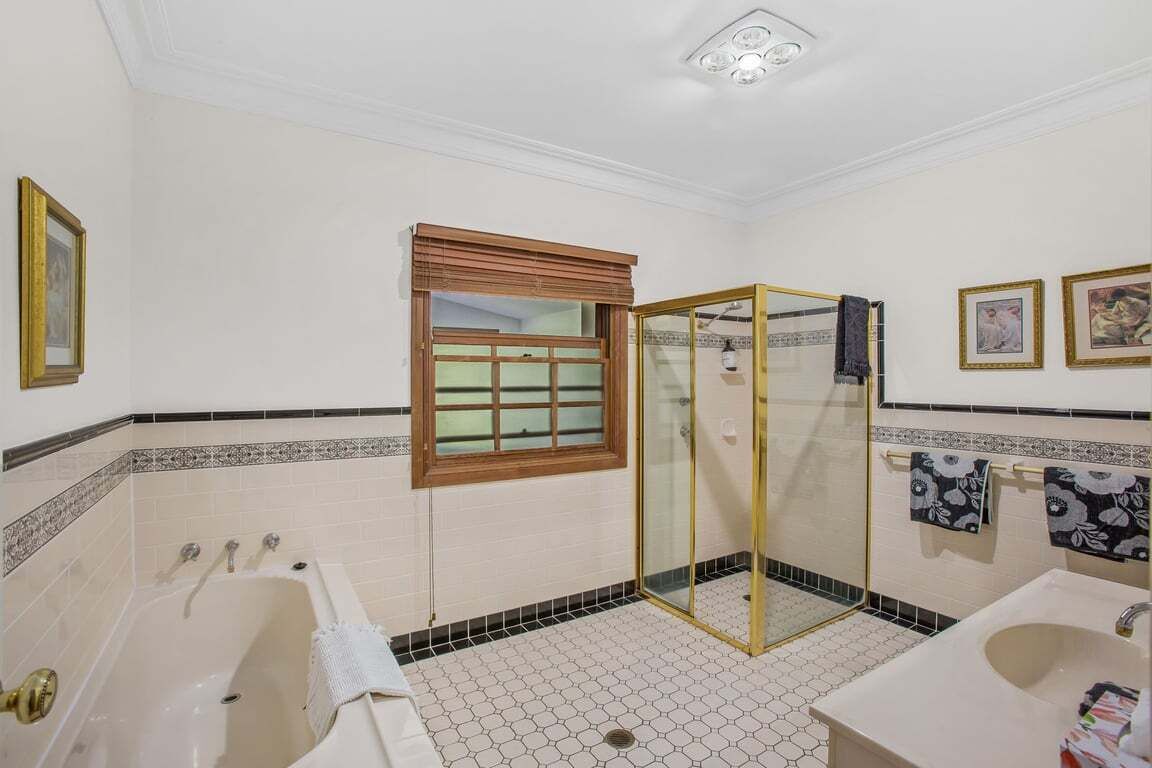 A bathroom with a bathtub, a glass-enclosed shower, a sink, and decorative tiles.