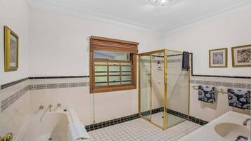 A bathroom with a bathtub, a glass-enclosed shower, a sink, and decorative tiles.