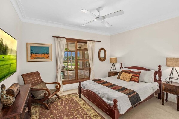 A bedroom with a bed, a desk, a chair, a window with curtains, a ceiling fan, and a painting on the wall. - Wahroonga Luxury Estate in Kangaroo Valley (Kangaroo Valley)