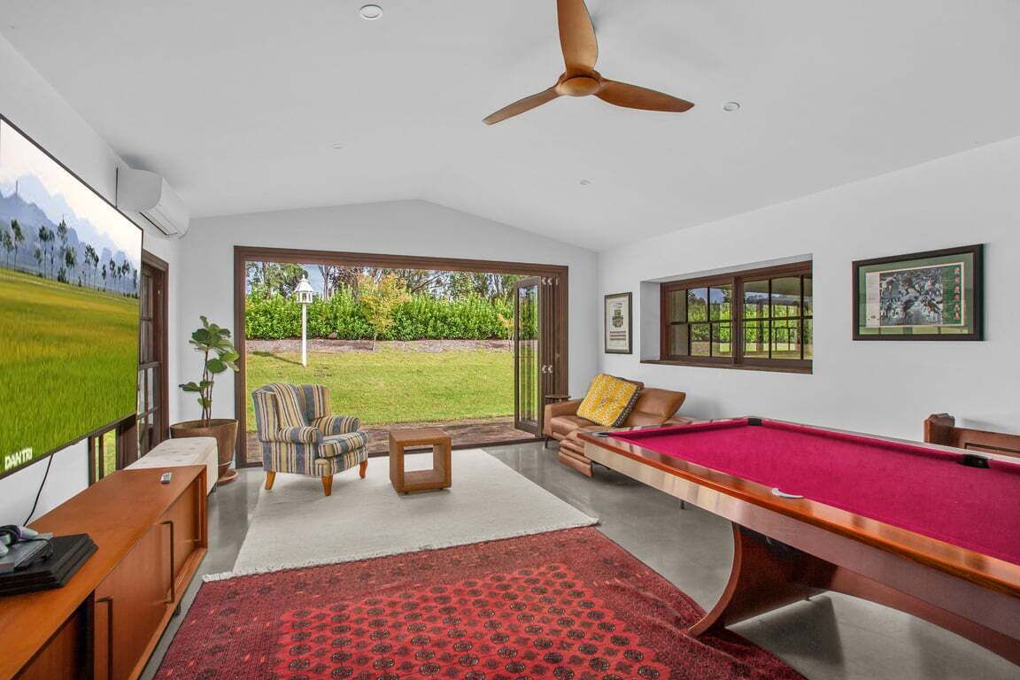 A room with a pool table, a sofa, a chair, and a television.