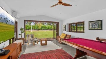 A room with a pool table, a sofa, a chair, and a television.