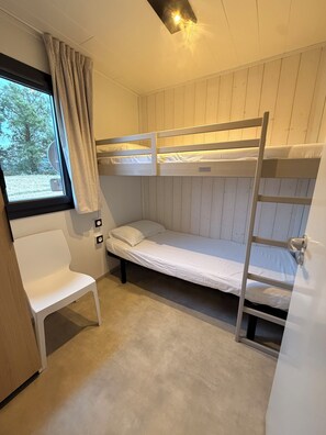 A bunk bed room with a window, a chair, and a door.