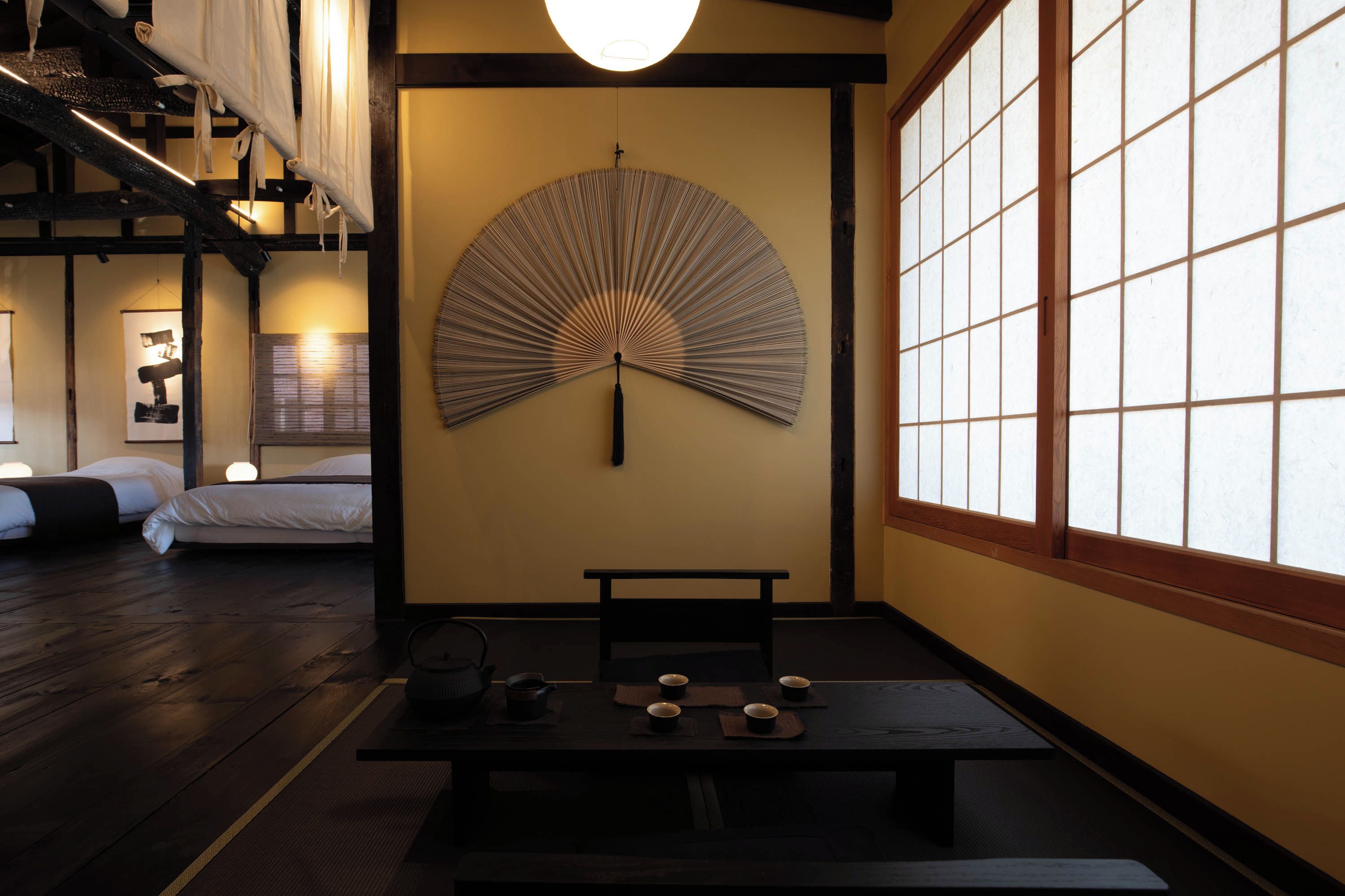 A traditional Japanese room with tatami flooring, a low table with cups and a teapot, and a large shoji screen.