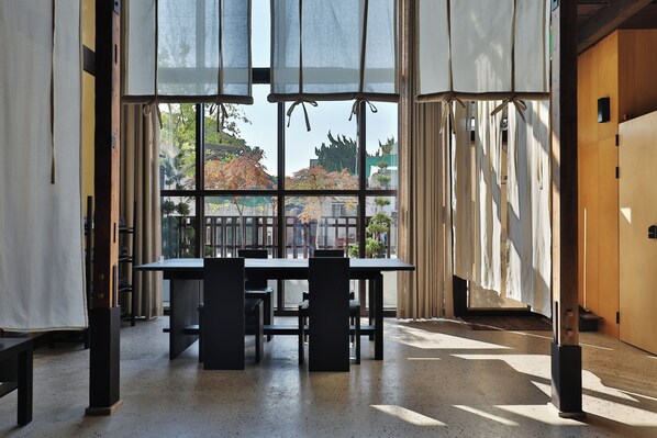 A room with a large window, a table, and chairs.