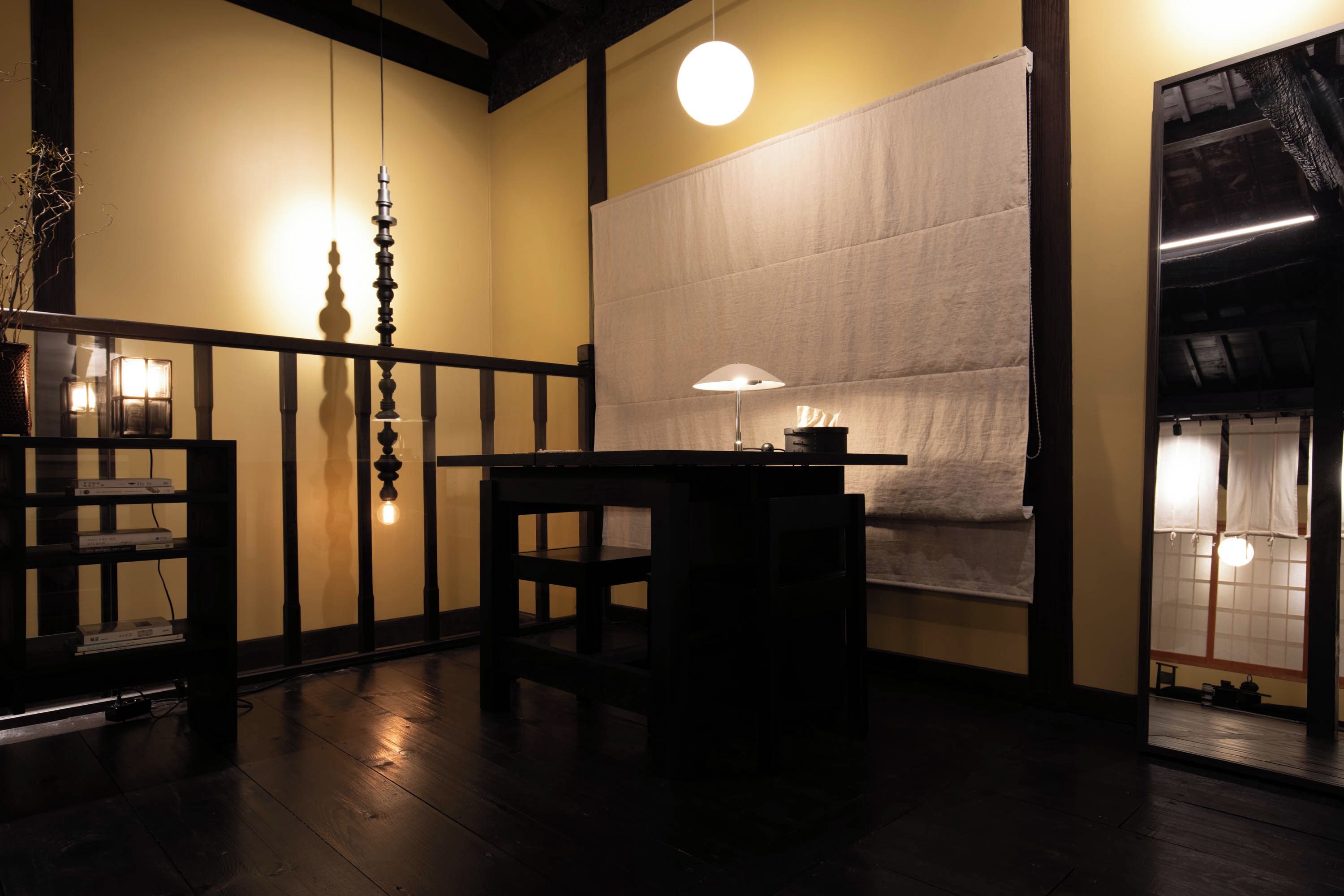 Una habitació tradicional japonesa amb fusta de tatami, una taula baixa amb una làmpada i una porta corredissa.
