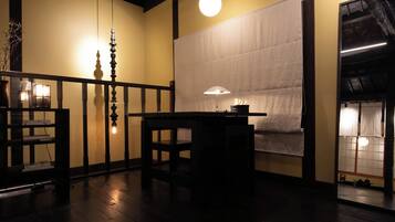 Una habitació tradicional japonesa amb fusta de tatami, una taula baixa amb una làmpada i una porta corredissa.