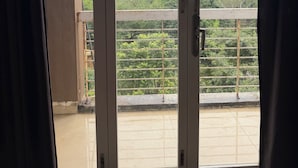 Vista a través de una puerta con barandilla metálica, que da a un balcón con vistas a una represa y montañas.