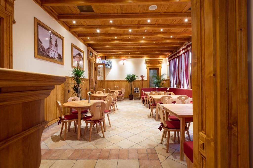 A restaurant with wooden furniture, tiled flooring, and framed pictures on the walls.