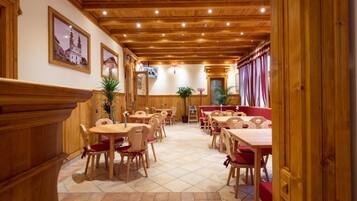 A restaurant with wooden furniture, tiled flooring, and framed pictures on the walls.