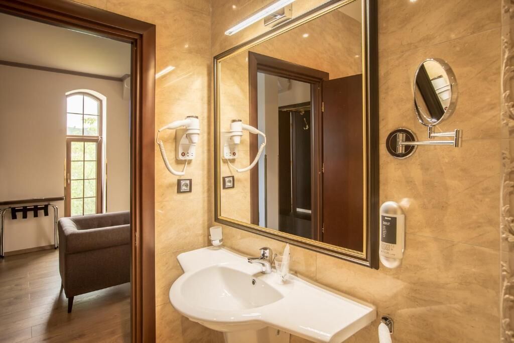 A bathroom with a large mirror, a sink, and a hairdryer.